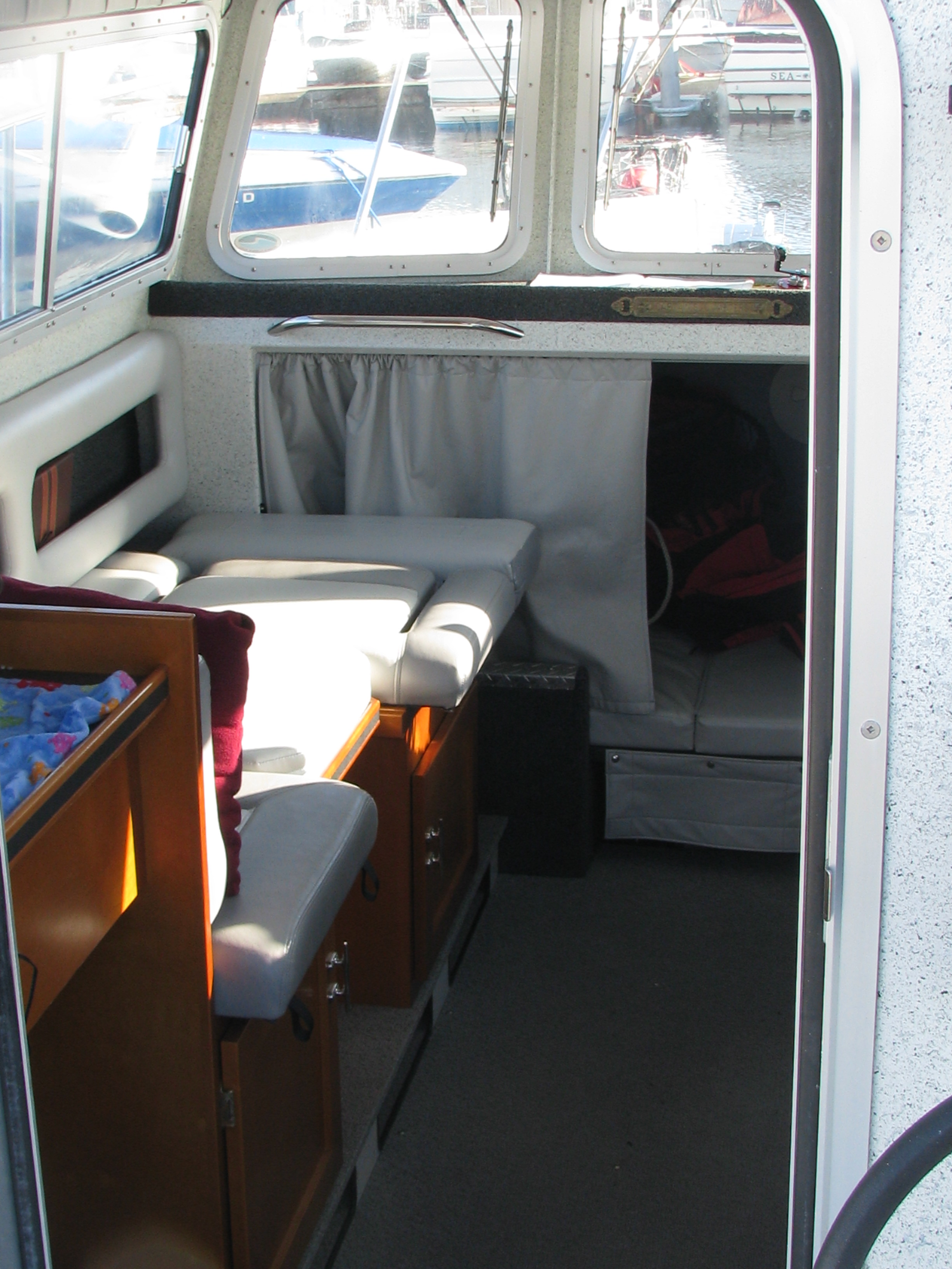 Interior of Highliner Charters' 26-foot Harbercraft Kingfisher fishing boat, featuring a cozy port-side bench and a fully enclosed cabin with a warm heater and private marine head.